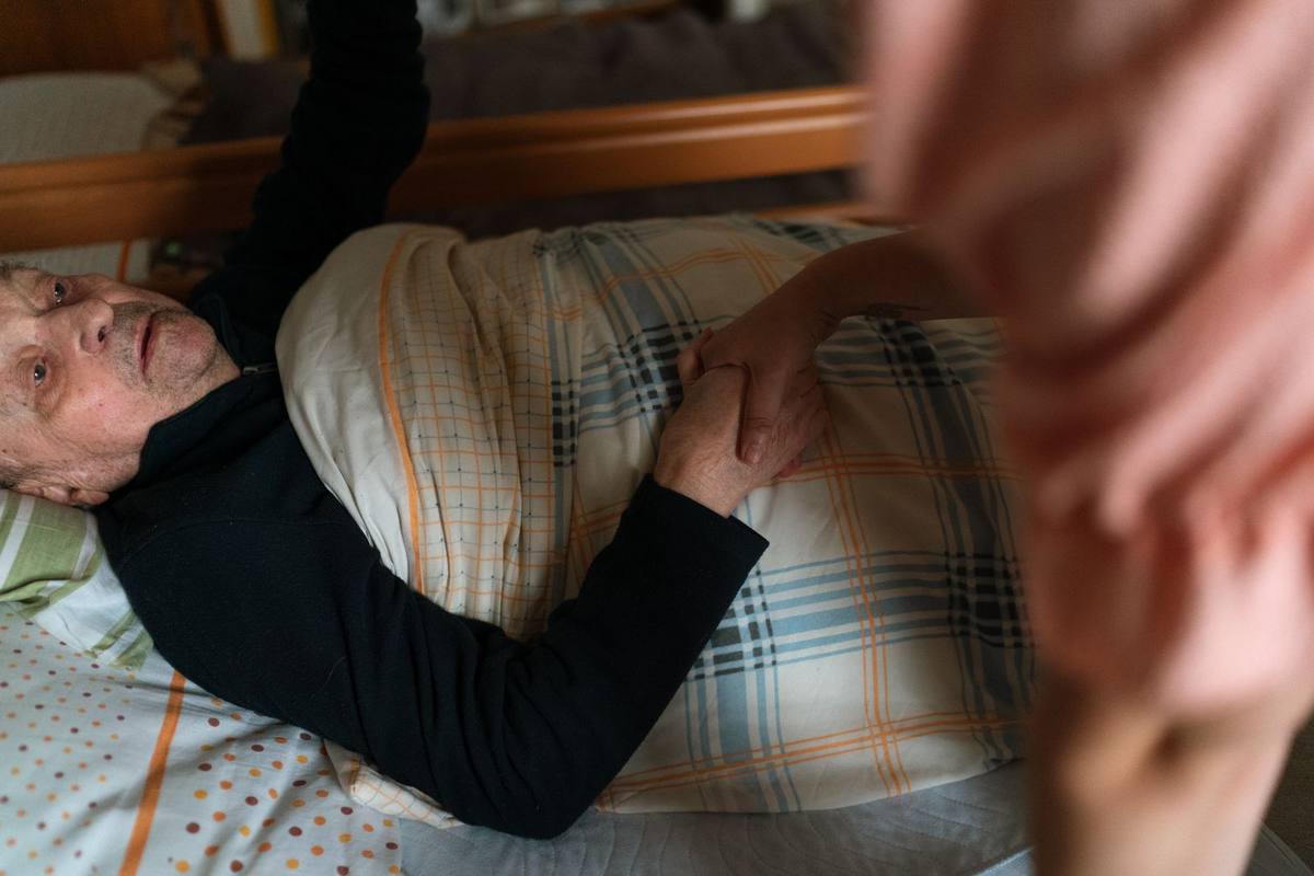 Caregiver gently holding the hand of a senior at home