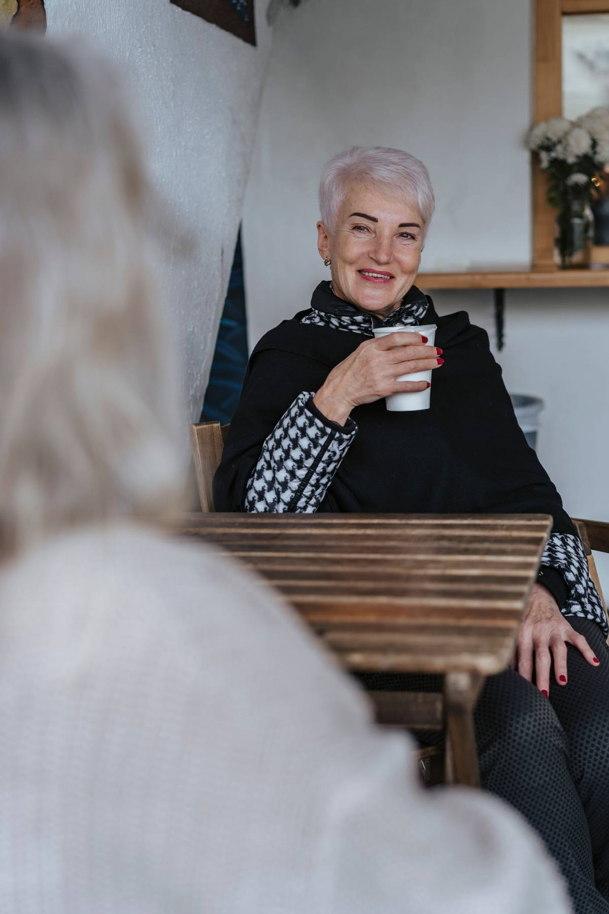 Smiling senior woman holding a warm coffee cup at home